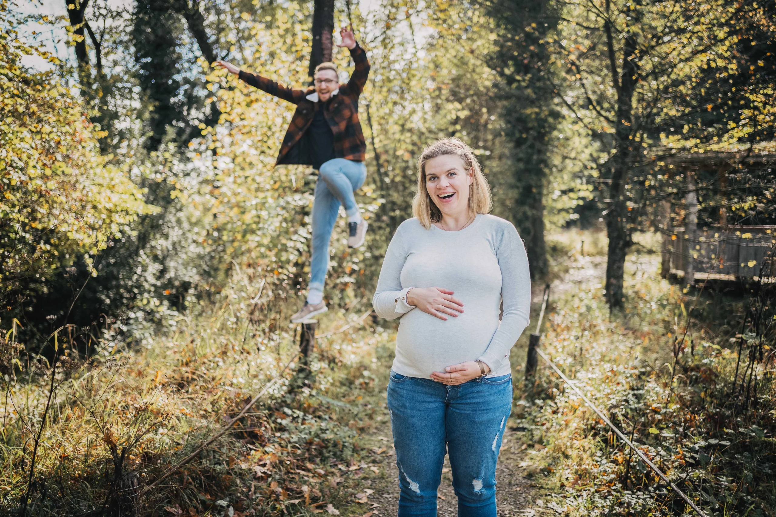 Auf dem Babybauchfoto hüpft der Mann im Hintergrund vor Freude in die Luft.