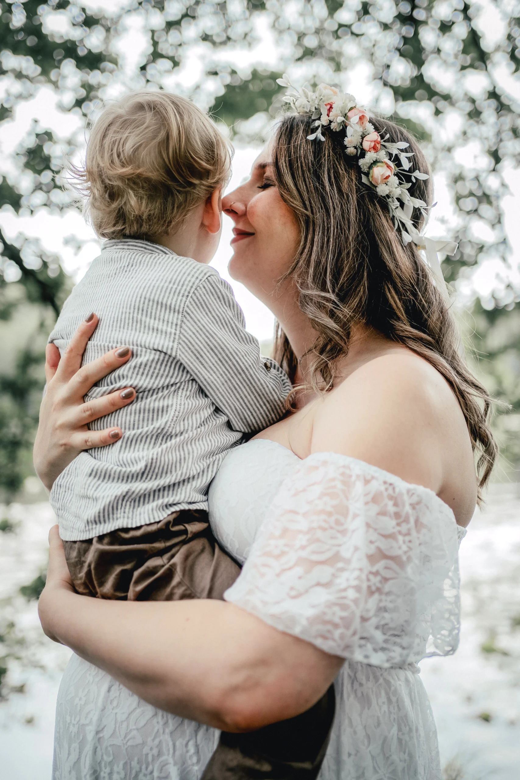 Mutter küsst ihr Kind liebevoll bei einem Outdoorshooting im Wald