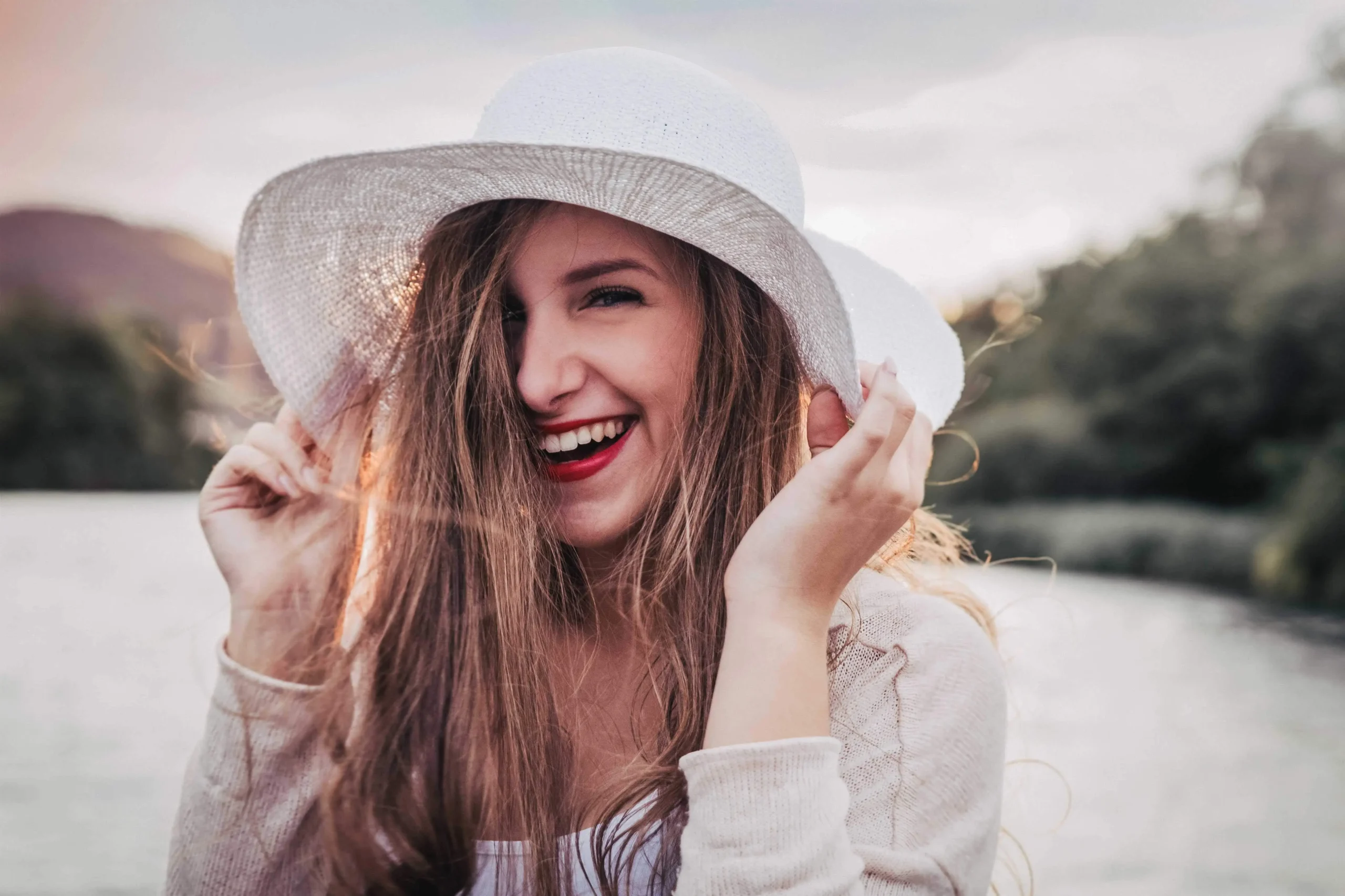 Portraitfoto von Alissa mit einem Hut auf dem Kopf und einem lachen im Gesicht