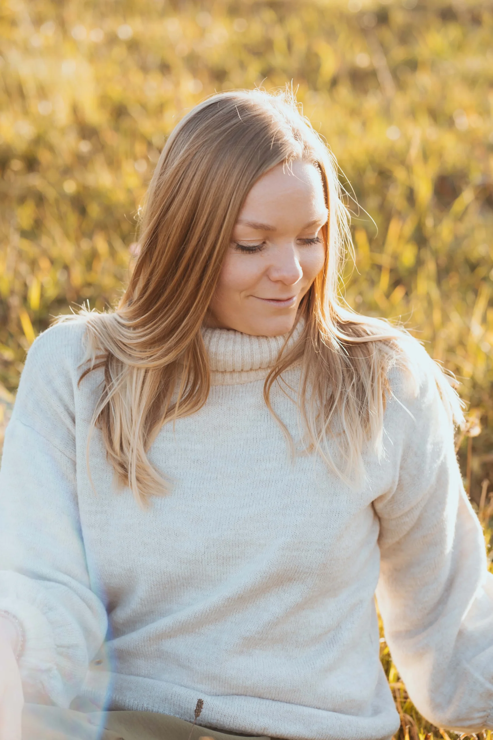 Warm eingepackt für ein Fotoshooting sitzt die junge Frau im Feld