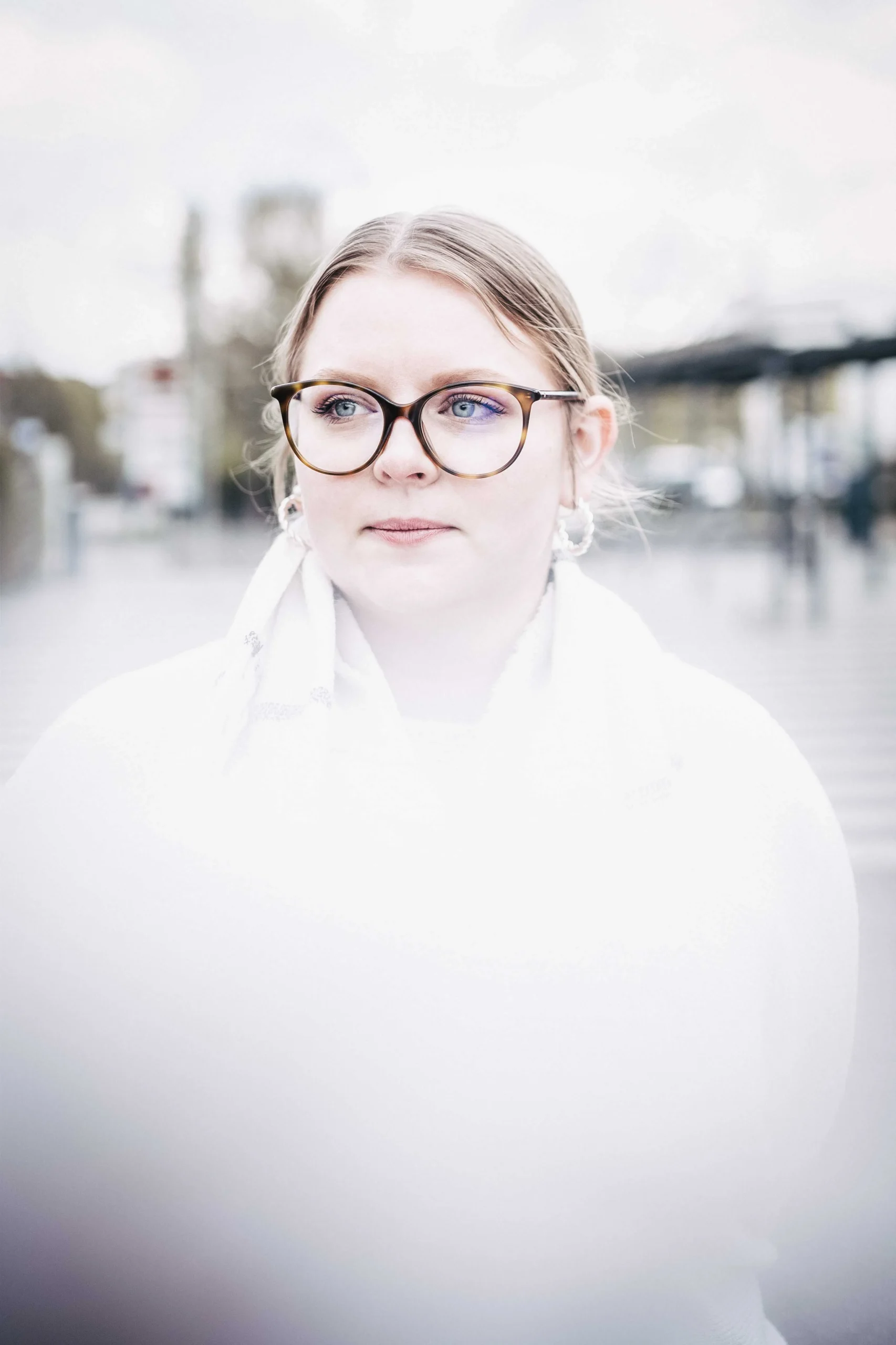 Ein Schaal in der Unschärfe des Fotos. Die Frau mit der Brille im Bildfokus